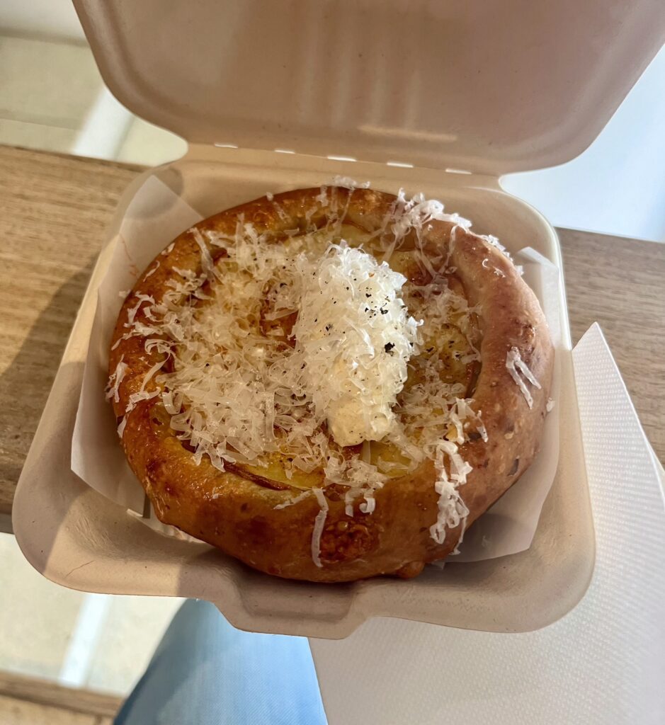 Looking down at a cheese and potato tart in a cardboard container on a table