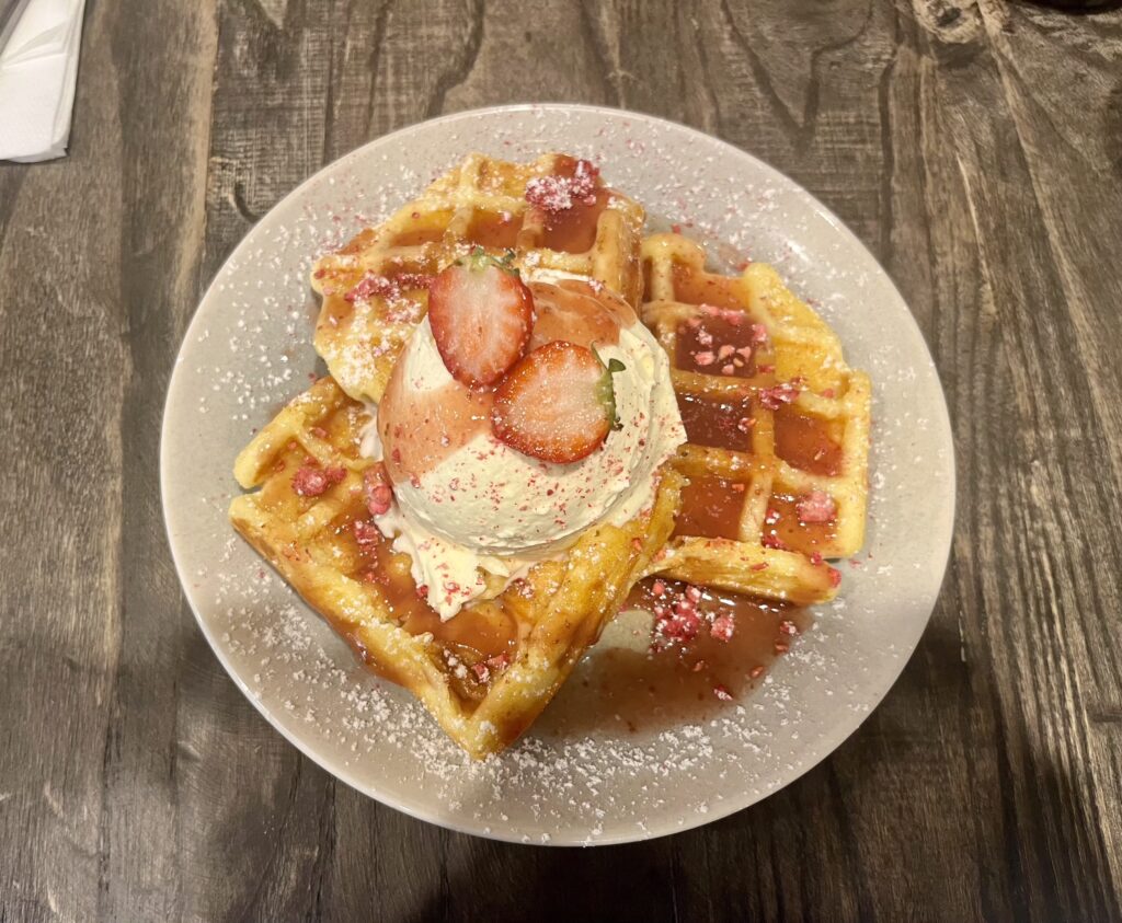 Looking down at strawberries on top of waffles with cream