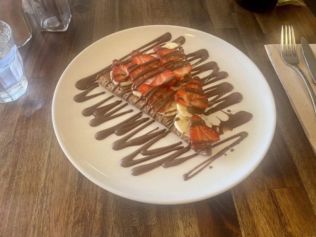 A white plate with a strawberry, banana, and chocolate galette