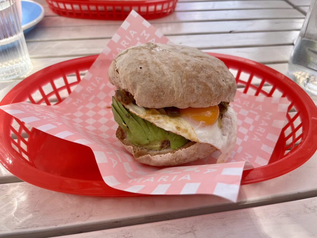 A breakfast burger with egg, avocado and chutney in a red basket